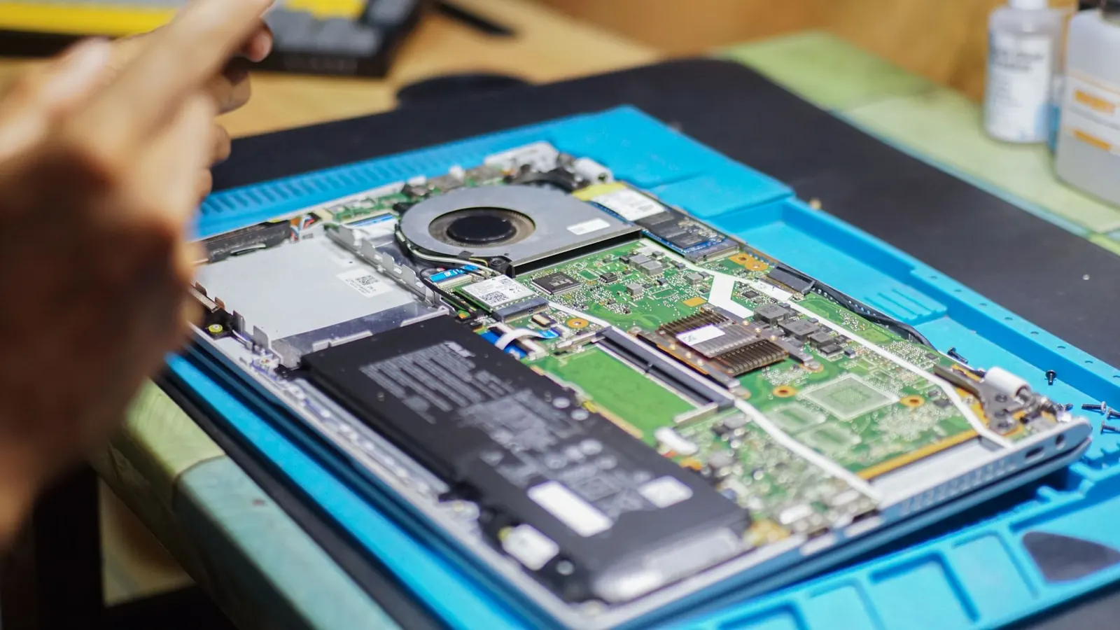 Mavi teknik servis matı üzerinde bakımı yapılan açık laptop